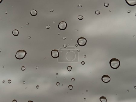 Regentropfen auf einem Fenster mit einem Hintergrund aus grauen Wolken