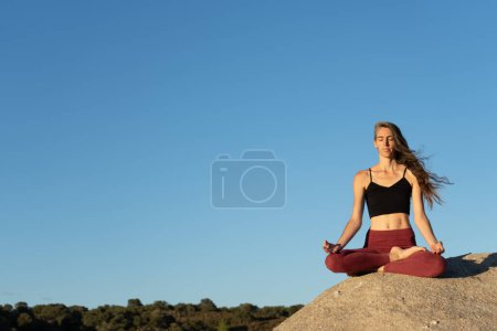 Frau meditiert in der Natur auf einem Felsen
