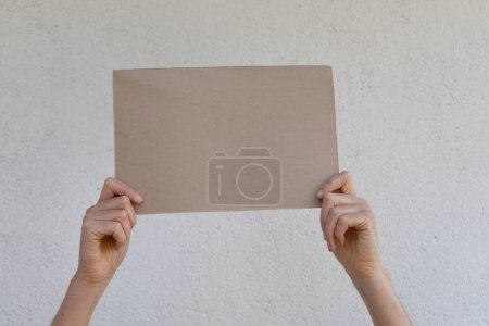 Téléchargez les photos : Affiche en carton vierge tenue par les mains d'une femme - en image libre de droit