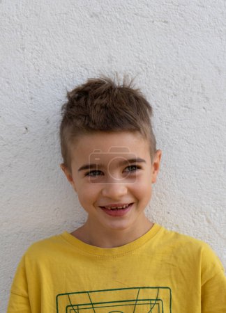 Photo for Portrait of a smiling boy with a yellow T-shirt and a white background - Royalty Free Image