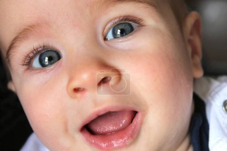 Portrait of a baby looking at the camera smiling with gray eyes