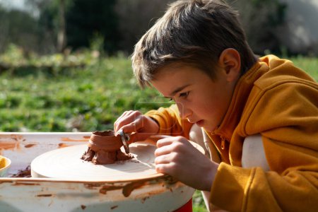 Foto de Niño al aire libre haciendo cerámica en la rueda de un alfarero - Imagen libre de derechos