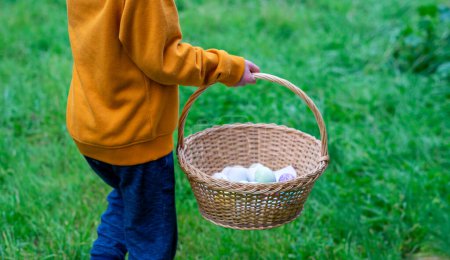 Niño llevando una cesta con huevos de Pascua al aire libre