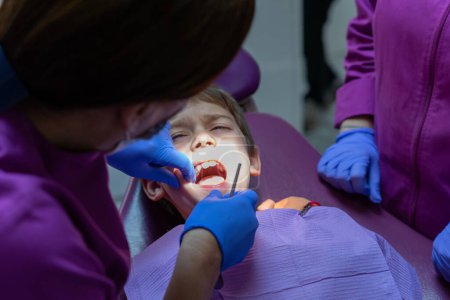 Foto de Niño con dolor de muelas en el consultorio del dentista - Imagen libre de derechos