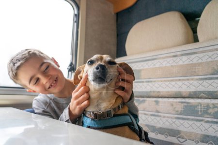 Téléchargez les photos : Garçon et chien souriant tout en voyageant en camping-car ensemble - en image libre de droit