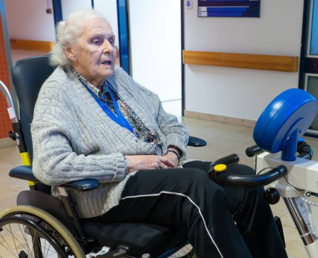 Elderly woman doing rehabilitation with a stationary bike in a hospital