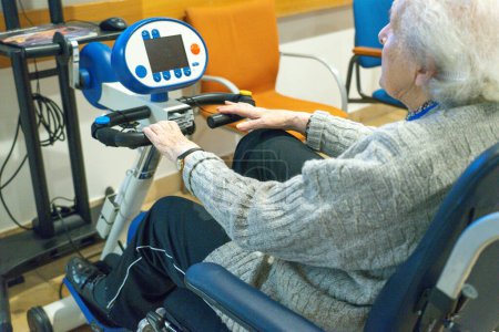 Elderly woman doing rehabilitation on a stationary bike in a hospital