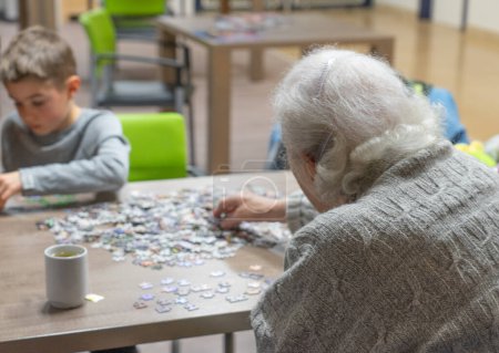 Photo for Senior woman doing a puzzle with a child in a nursing home - Royalty Free Image