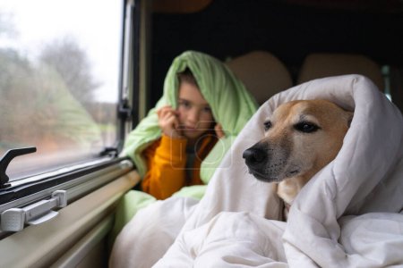 Téléchargez les photos : Garçon avec son chien dans le lit d'un camping-car couvert de couettes - en image libre de droit