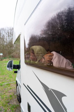 Téléchargez les photos : Garçon et son chien de compagnie dans un camping-car en hiver - en image libre de droit