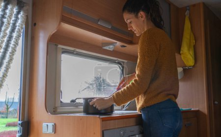 Téléchargez les photos : Femme cuisine à l'intérieur d'un camping-car - en image libre de droit