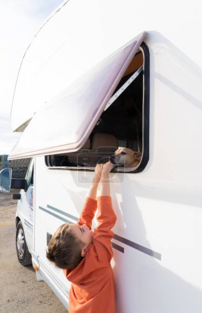 Téléchargez les photos : Garçon et chien voyageant dans un camping-car ensemble - en image libre de droit