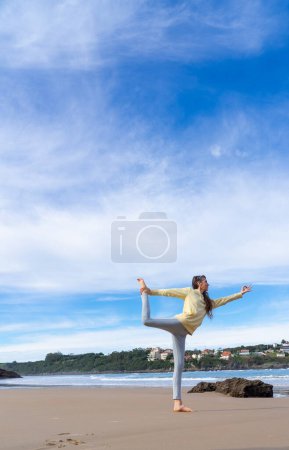 Téléchargez les photos : Femme faisant ballerine yoga pose sur la plage - en image libre de droit