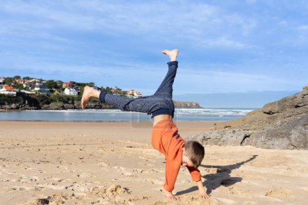 Photo for Boy doing cartwheel on a beach - Royalty Free Image