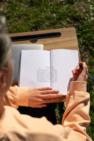 Foto de Mujer con un cuaderno en blanco trabajando fuera - Imagen libre de derechos