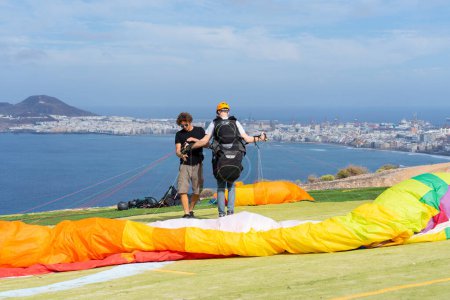 Man learning to paraglide on an island and paragliding teacher checking that all the material is correct