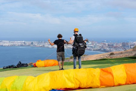 Man learning to use the controls of a paraglider with an instructor