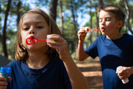 Niños jugando con burbujas de jabón en el bosque