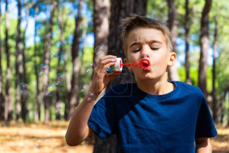 Child blowing bubbles with a bubbler in nature