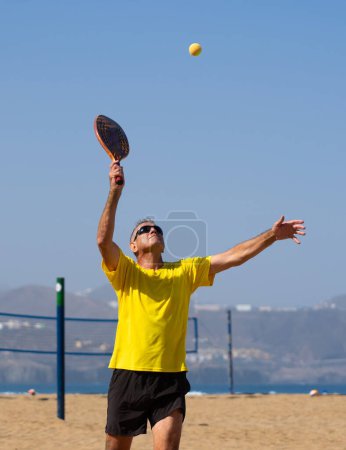 Man over 60 years old playing beach tennis. Senior man with a healthy lifestyle