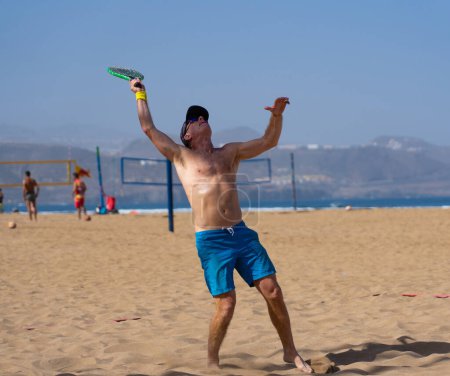 Mature man actively playing beach tennis