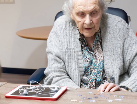 Téléchargez les photos : Femme âgée concentrée faisant un puzzle - en image libre de droit