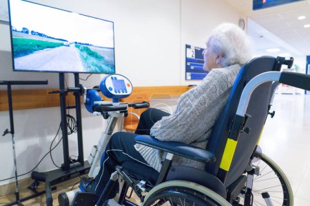 Ältere Frau bei der Rehabilitation auf einem stationären Fahrrad in einer Reha-Klinik