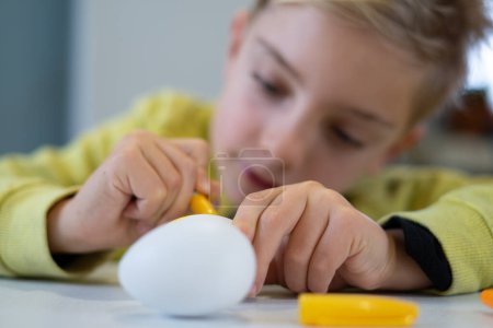 Boy painting an easter egg at home