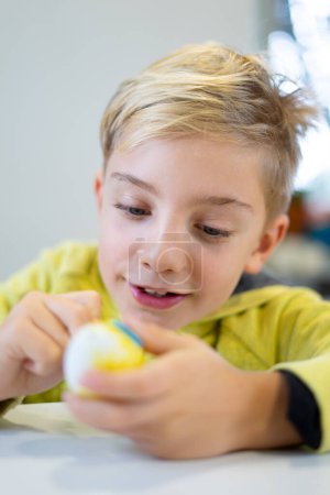 Happy child decorating an Easter egg with marker