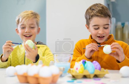 Téléchargez les photos : Les enfants s'amusent à peindre des œufs pour Pâques - en image libre de droit