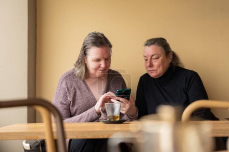 Reife Frauen schauen gemeinsam aufs Handy