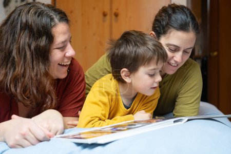 Familie mit zwei Müttern und ihrem Sohn schaut sich zu Hause ein Fotoalbum an