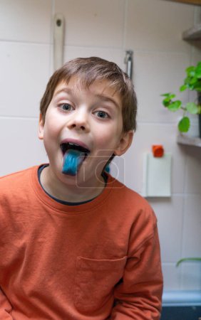 Junge zeigt seine blaue Zunge für ein Bonbon