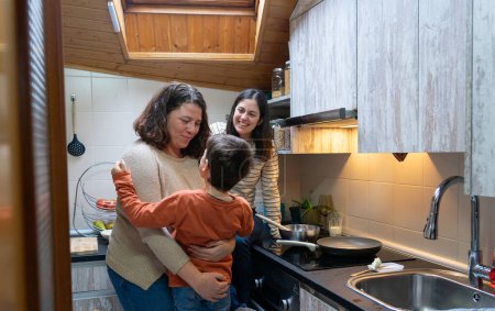 Family of two lesbian mothers and their son together in the kitchen of their home