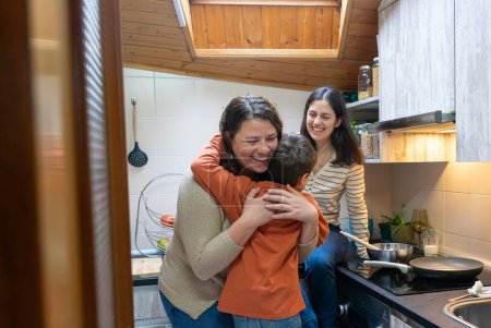 Mutter und Sohn umarmen sich in der Küche. lgbtqia + Familie kocht zusammen
