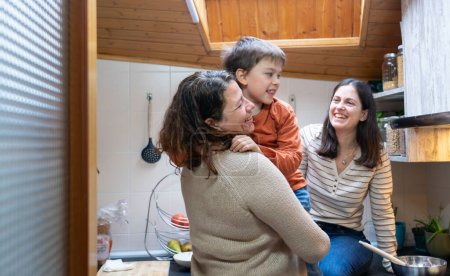 Familia LGBT de dos madres y un niño feliz en la cocina de su casa