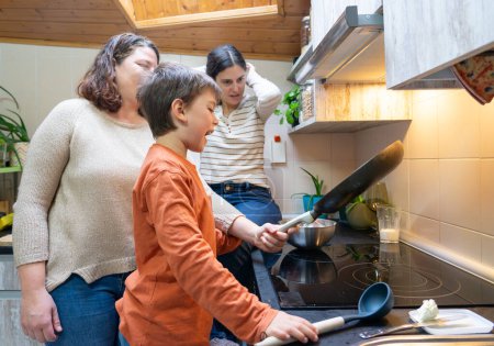 Family of two lesbian mothers and their son cooking at home