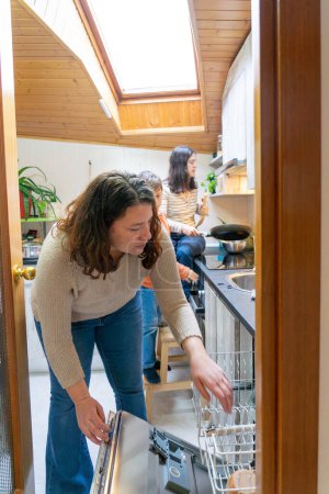 Familia lesbiana con un hijo haciendo la vida cotidiana en la cocina de su casa