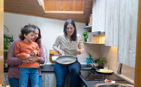 Famille LGBT de deux mamans et un enfant cuisinant des crêpes maison dans la cuisine de leur maison