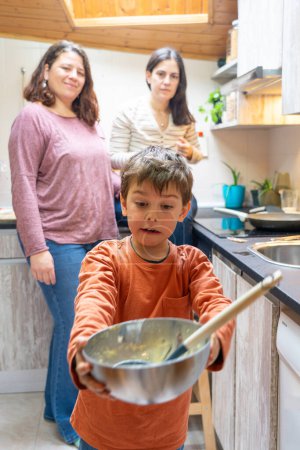 Child making homemade dough with his mothers in the kitchen at home
