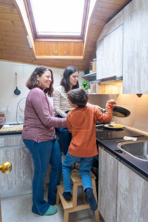 Familia de dos madres lesbianas y su hijo cocinando juntos en la cocina en casa
