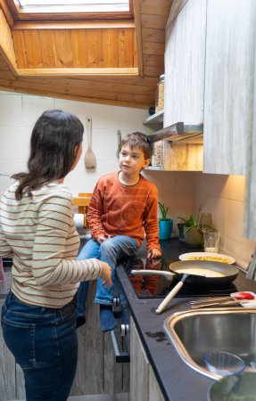Boy cooking pancakes with his mother at home