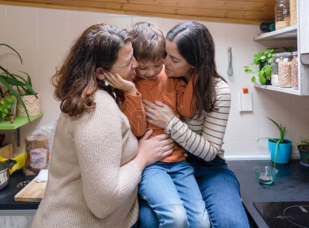 Niño con sus dos madres mimándose en la cocina de su casa