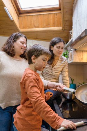 Familia LGBTQIA de dos madres lesbianas y su hijo cocinando juntos en casa