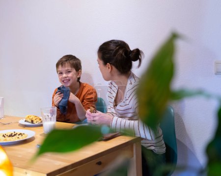 Glückliches Kind isst zu Hause mit seiner Mutter hausgemachte Pfannkuchen
