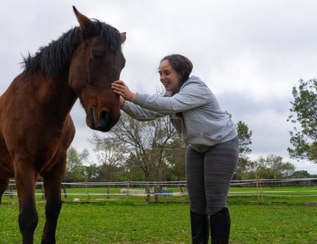 Glückliche junge Frau kümmert sich um ihr Pferd und streichelt es