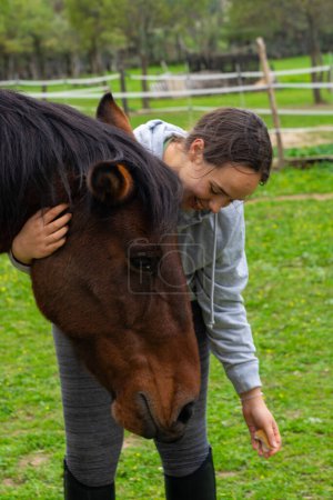 Young woman smiling stroking a horse