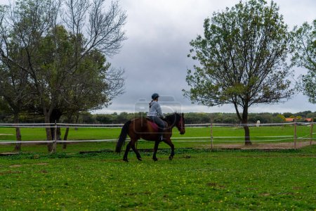 Adolescente apprendre à monter à cheval à une école d'équitation