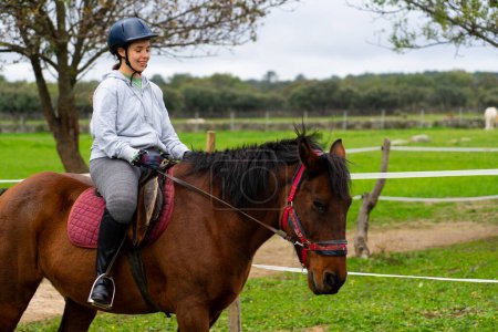 Photo for Young woman receiving horse riding lessons at a riding stable - Royalty Free Image