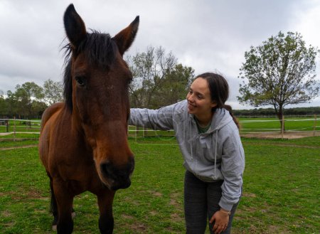 Téléchargez les photos : Adolescente caressant un cheval dans la nature - en image libre de droit